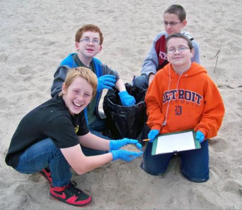 Four boys doing Adopt-A-Beach clean up image.