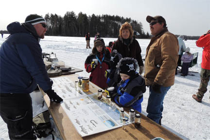 Family learning about ice fishing image.